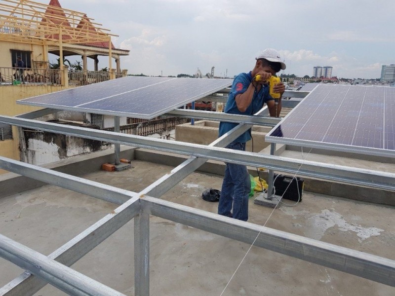 Thợ lắp tấm pin lên khung thép mạ kẽm trên mái