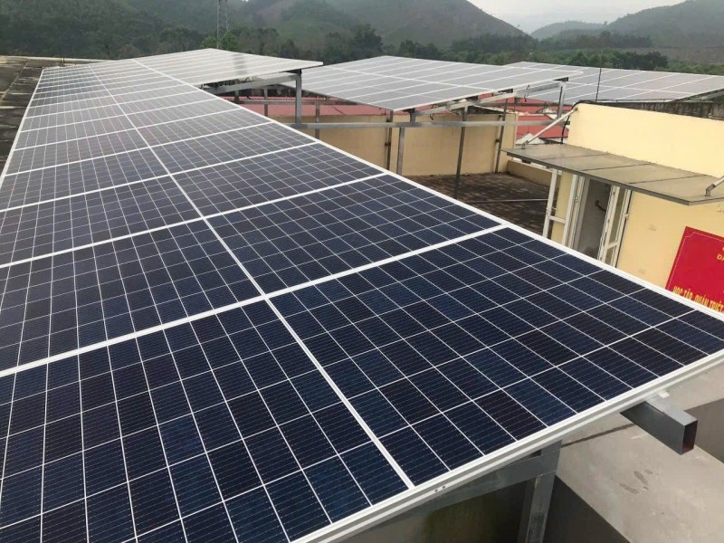 Khung giàn tấm pin trên mái nhà, phía sau là đồi